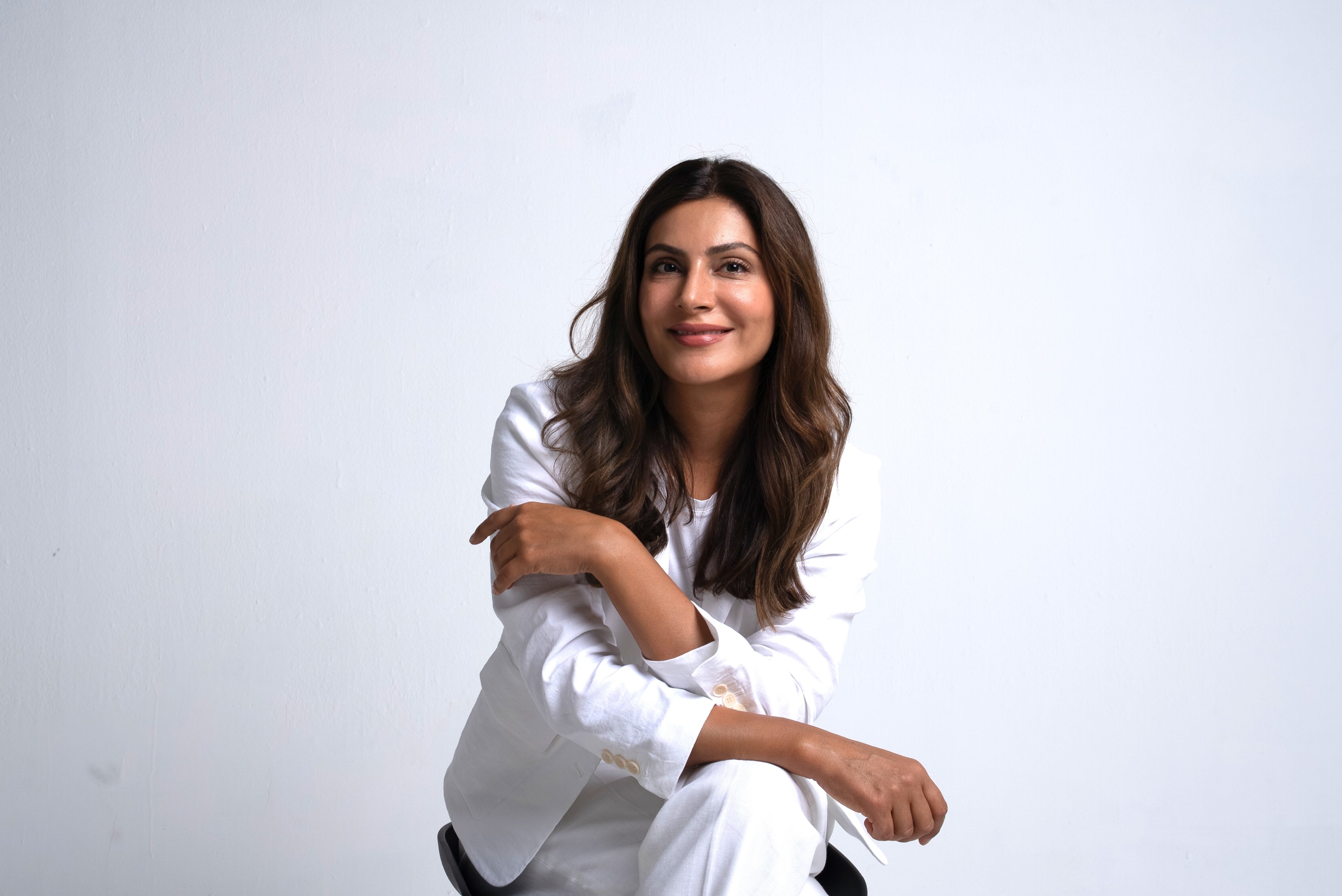 Dr. Lamees in a white outfit sitting against a plain background